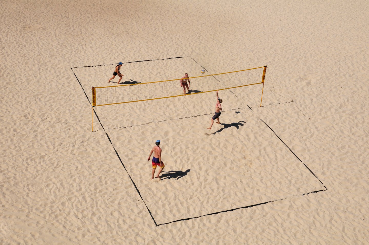 Persone che giocano a beach volley in una giornata di sole.