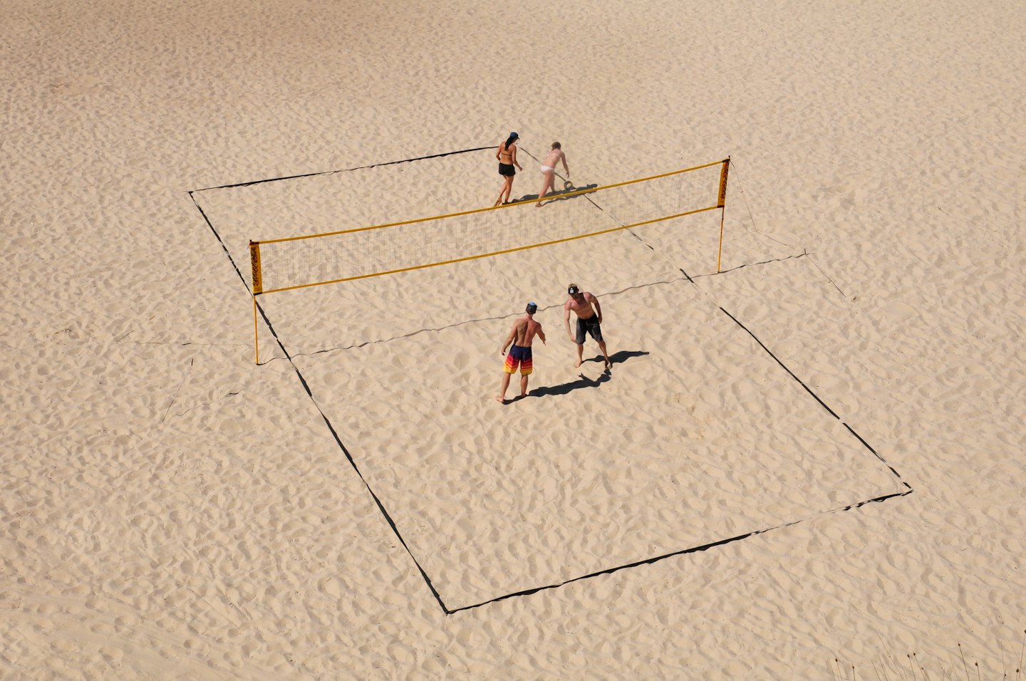Quattro persone giocano a beach volley.