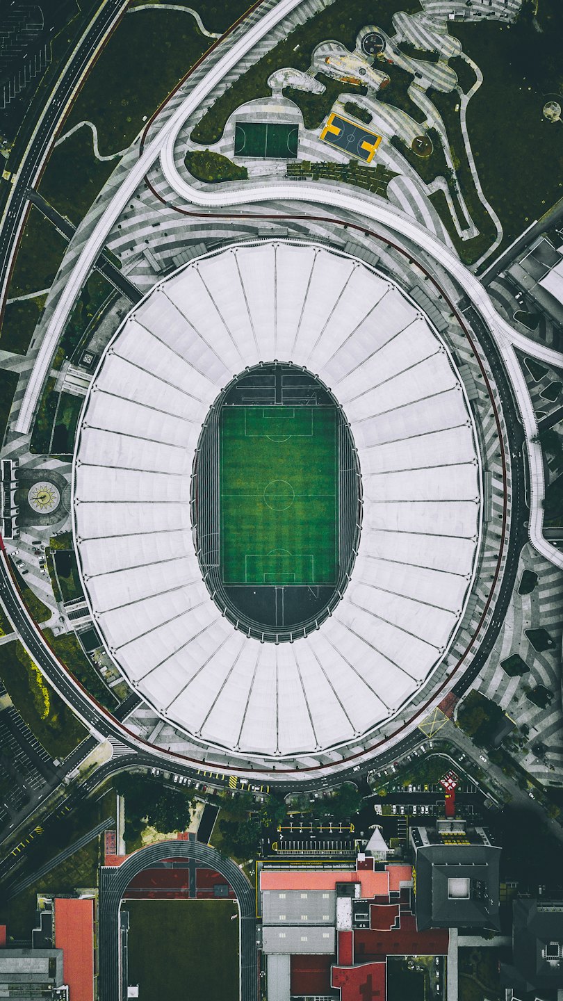 Vista aerea di un moderno stadio sportivo con un campo da calcio verde.