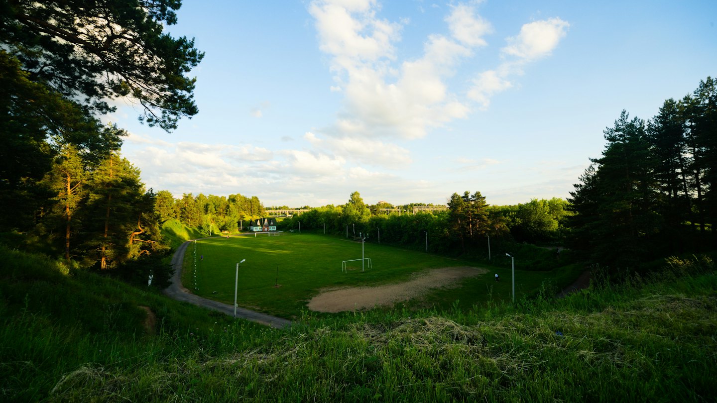 Campo sportivo in una valle circondata da alberi verdi.