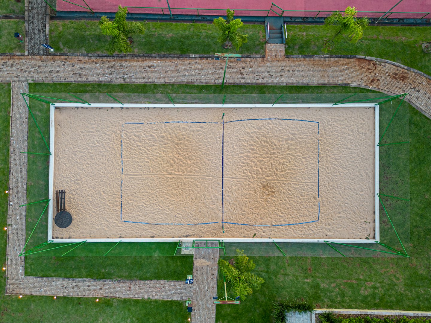 Campo da pallavolo da spiaggia vuoto con linee di confine blu su erba verde.